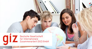 Vier junge Menschen betrachten einen Globus auf einem Tisch